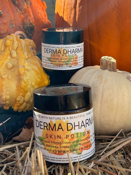 Two jars of Dera Dharma on a bed of hay with pumpkins and gourds.